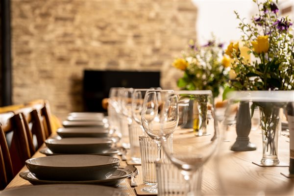 Dining table set for large group with flowers, candles and wine glasses.